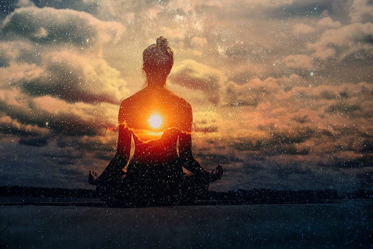 Silhouetted person meditating with a galaxy superimposed within their body. It symbolizes the infinite nature of the true Self.