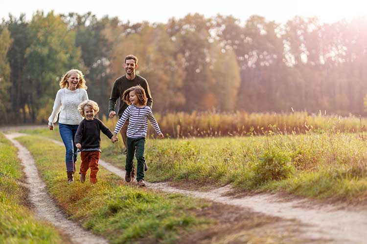 Family walking joyfully on a nature path at sunset, symbolizing presence and connection in mindful Buddhist parenting.
