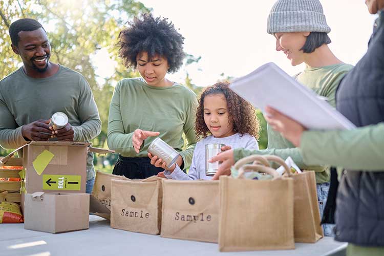 Family and children sorting canned goods at a donation table, demonstrating how Buddhist parenting teaches values through everyday compassionate actions.