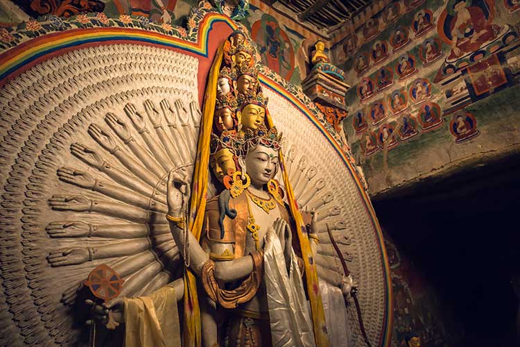A statue of Avalokiteshvara, the Bodhisattva of Compassion, depicted with serene expression and multiple arms, symbolizing infinite compassion and the willingness to help all beings.