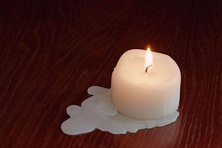 A close-up of a candle burning down, its flame flickering as melted wax drips, symbolizing the fleeting nature of life and time.