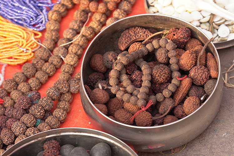 Assortment of rudraksha mala beads displayed in bowls and on cloth, highlighting the importance of choosing ethically sourced and lovingly made meditation tools.