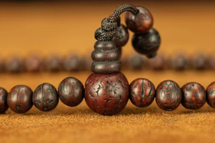 Close-up of a dark wooden guru bead on a mala, symbolizing a spiritual checkpoint for reflection, gratitude, and reconnection during meditation.