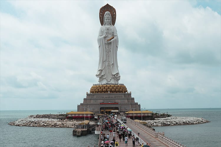A towering statue of Kuan Yin stands at the end of a long bridge over the sea. It symbolizes her role as a bridge between two worlds—earth and spirit.