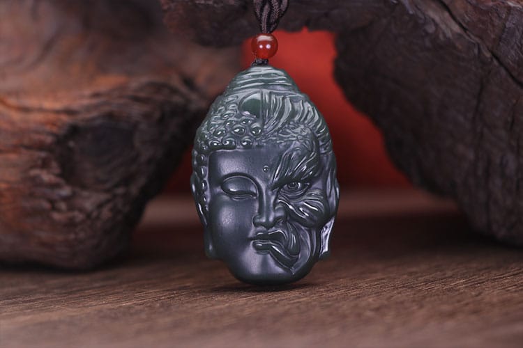 A carved jade pendant showing a serene Buddha face fused with a wrathful demon. It represents the Buddha’s victory over Mara and the deeper spiritual message of overcoming inner obstacles.