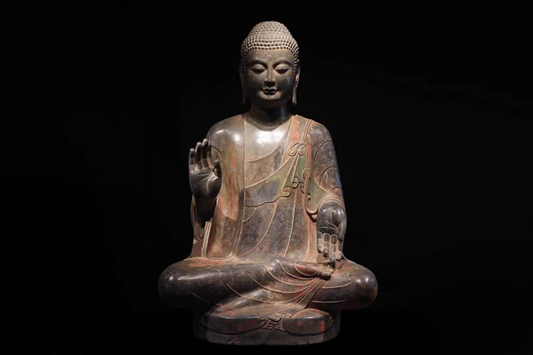 A stone Buddha statue seated cross-legged in meditation.
