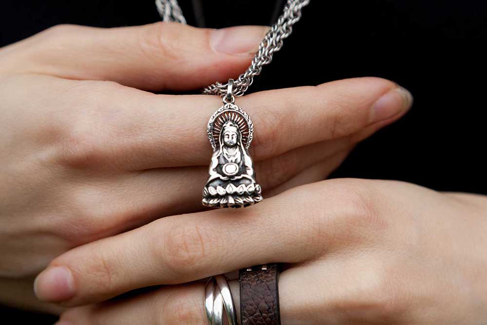 Someone hold a silver Guanyin pendant in their hands