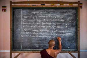 Monk writing on chalkboard