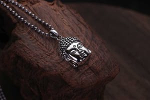 A silver pendant depicting the Buddha's face