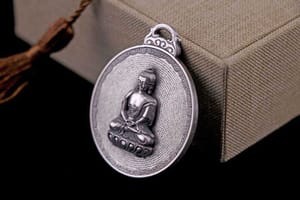 A silver medallion depicting The Buddha with the Surangama sutra encicling him