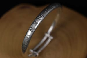 A silver bracelet engraved with the Om Mani Padme Hum mantra in the Siddham script